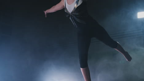 in slow motion in the smoke, a girl athlete stands with her arms raised after performing exercises. welcome gesture with your hands.