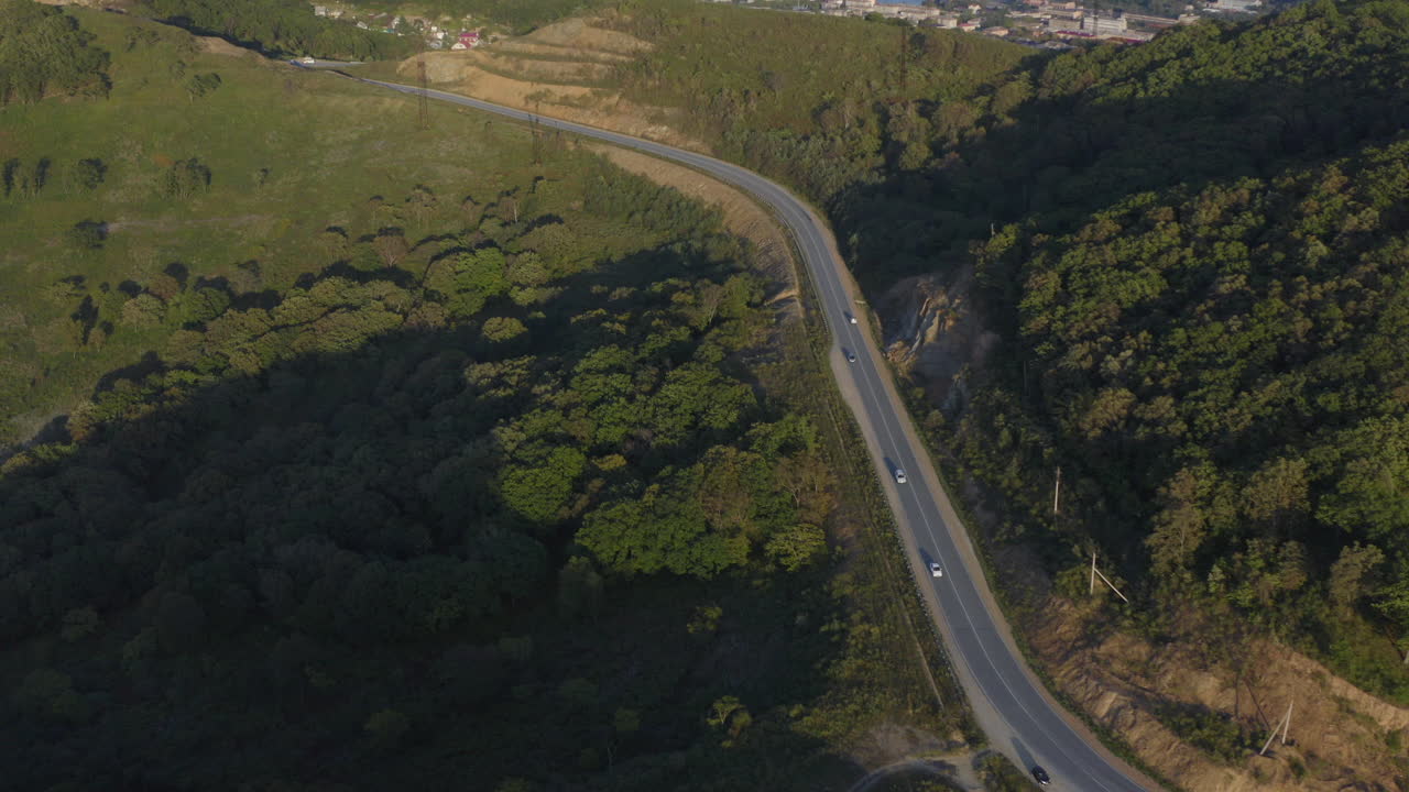 극동 러시아 일몰에 산악 도로와 도시를 배경으로 이동하는 자동차