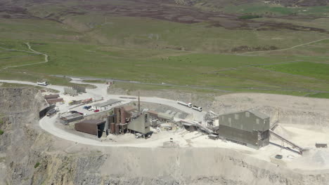 An-aerial-view-of-a-working-asphalt-quarry-building-with-the-quarry-cut-in-the-foreground-and-countryside-in-the-background,-Yorkshire,-UK
