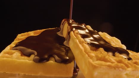 Static-shot-of-delicious-waffles-with-vegan-chocolate-sauce-flowing-down-against-a-black-background