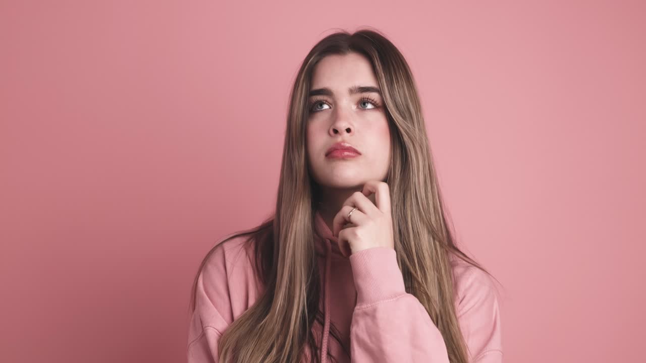 Pensive young woman standing with finger at mouth