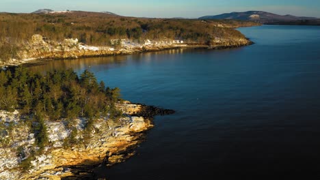 aerial footage curving around a snow dusted rocky peninsula on the maine coast