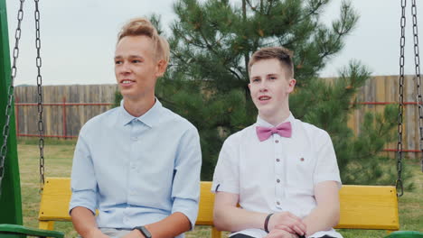 two high school graduates ride on a swing