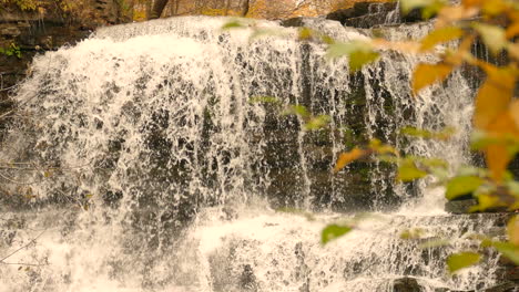 powerful autumn forest waterfall splashing down rocky landscape, static view