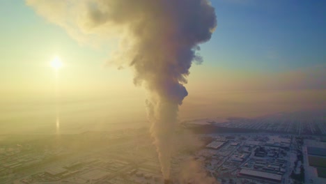 industrial smoke emission over a snowy city at sunrise/sunset