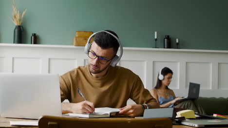 vista de cerca de un estudiante con auriculares y usando una computadora portátil sentada en la mesa