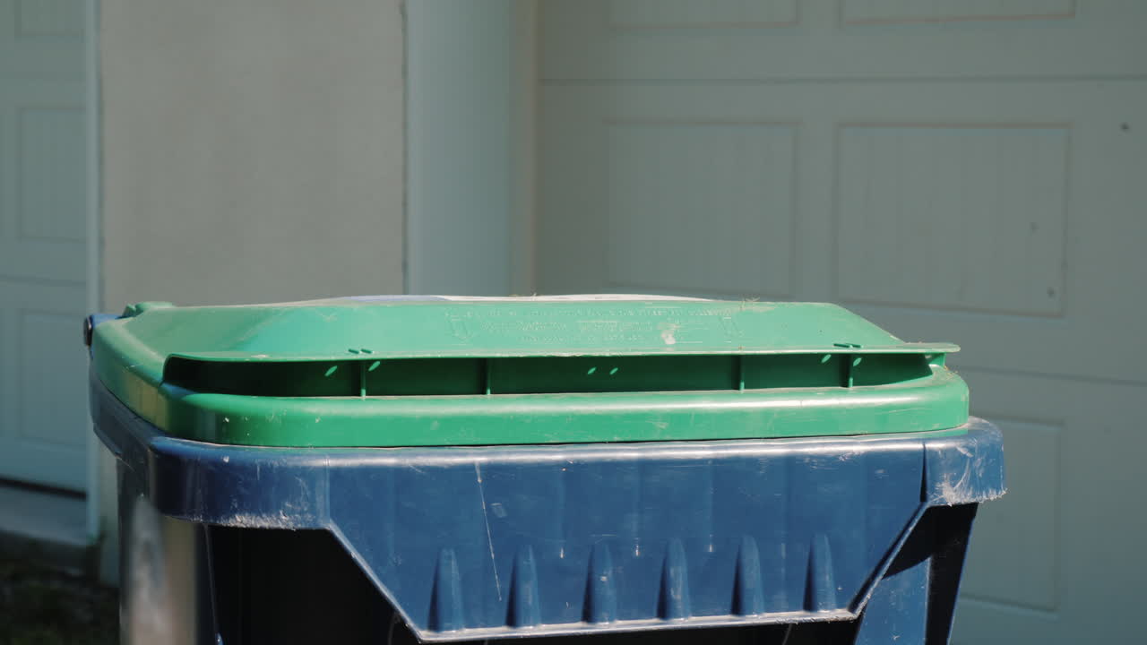 el ama de casa arroja una bolsa de basura al tanque cerca de la casa