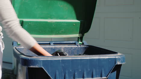 el ama de casa arroja una bolsa de basura al tanque cerca de la casa