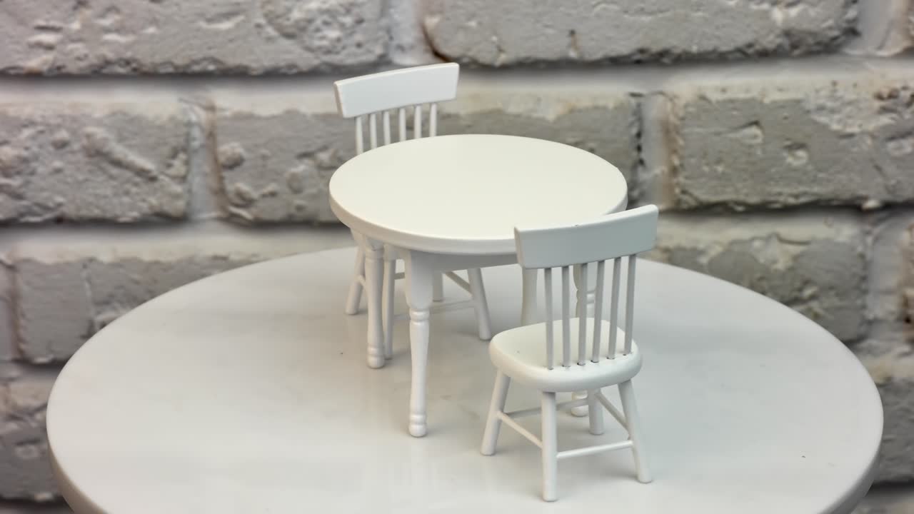 Toy round table and two little chairs beside. Beautiful pieces of dolly furniture at rotating table. White wall background.