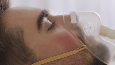 close up of a sick man lying on bed breathing through oxygen mask