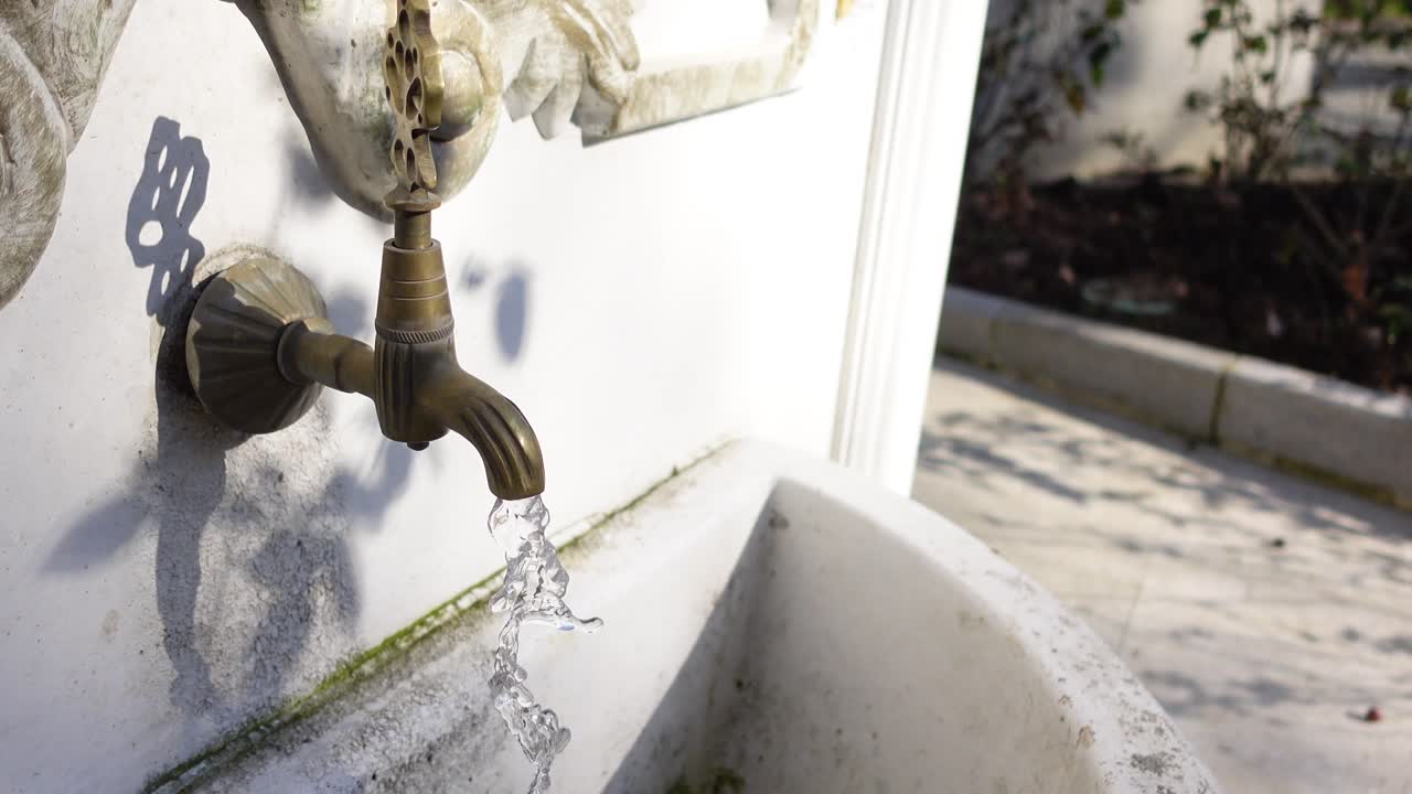 Primo piano di una fontana in pietra con acqua che scorre da un rubinetto in ottone