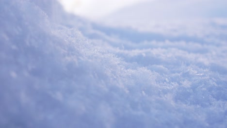 4k close up footage, capturing fresh powder snow falling on top a snow mound, in an icy cold winter landscape setting