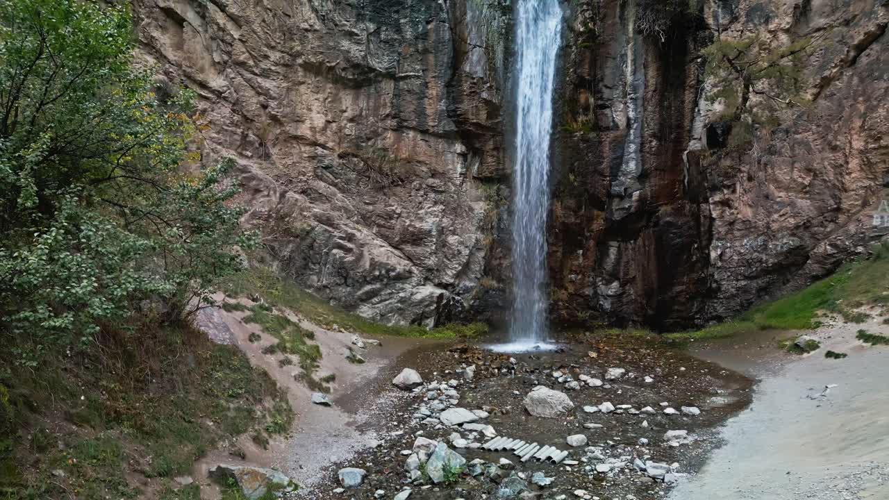 Aerial reveal, remote elevated terrain, waterfall cliffs, valley scene