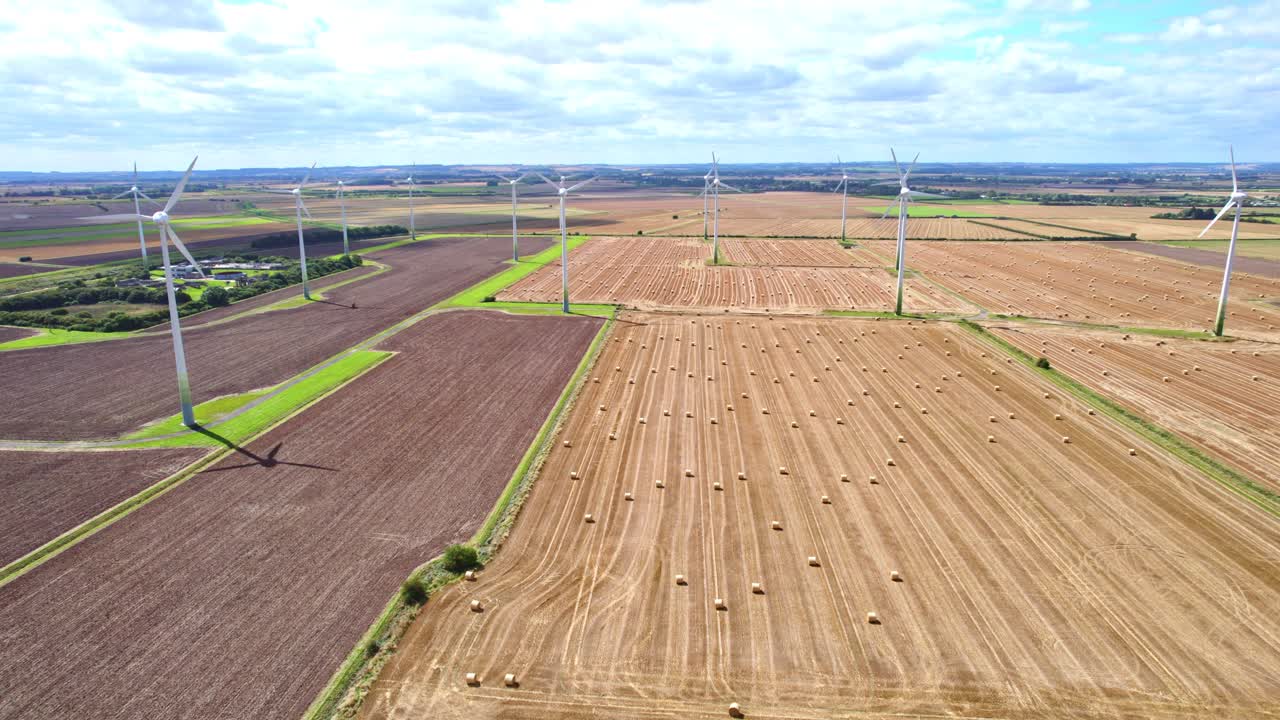 Above, an aerial video reveals a picturesque scene: wind turbines turning gracefully in a Lincolnshire farmer's recently harvested field, with golden hay bales in view