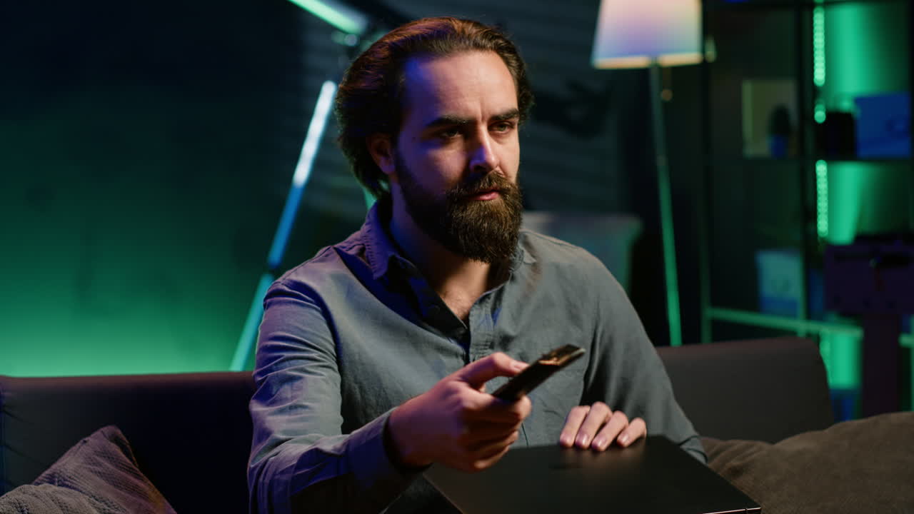 hombre viendo una noticia impactante en la televisión en un apartamento