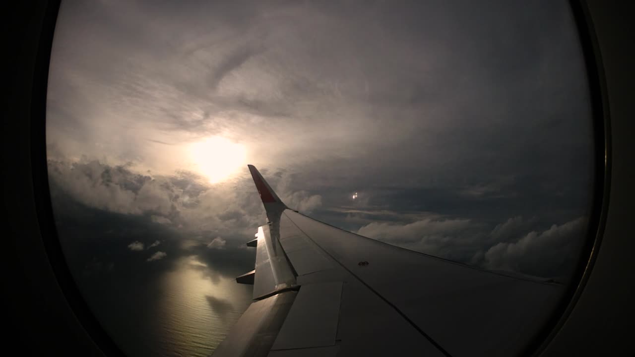 Solnedgang og smukke skyer set fra flyvinduet i venstre side vækker rejselysten.
