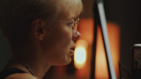 female podcast host talking into microphone in recording studio