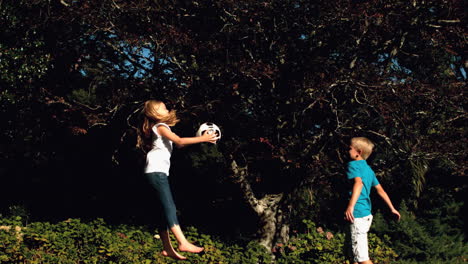 siblings having fun with a football on a trampoline