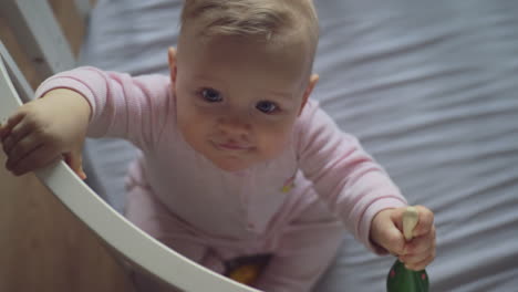 a top view of a baby girl trying to stand up in a crib