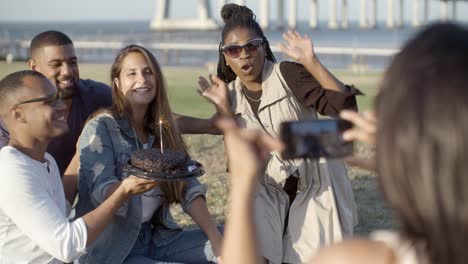 smiling friends posing with cake for photo.