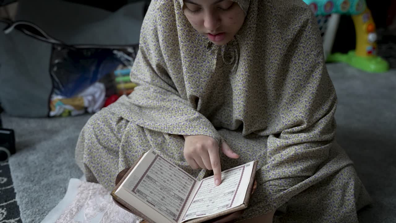Young Muslim Woman Reading Quran At Home - Close Up