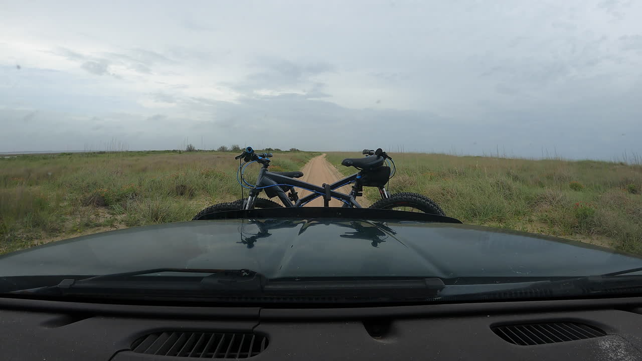 Dashboard Hyperlapse of an adventure seeking mountain biking couple traveling along a sandy gravel road with dark gloomy clouds above