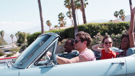 Young-adult-friends-on-the-road-in-a-classic-convertible-car