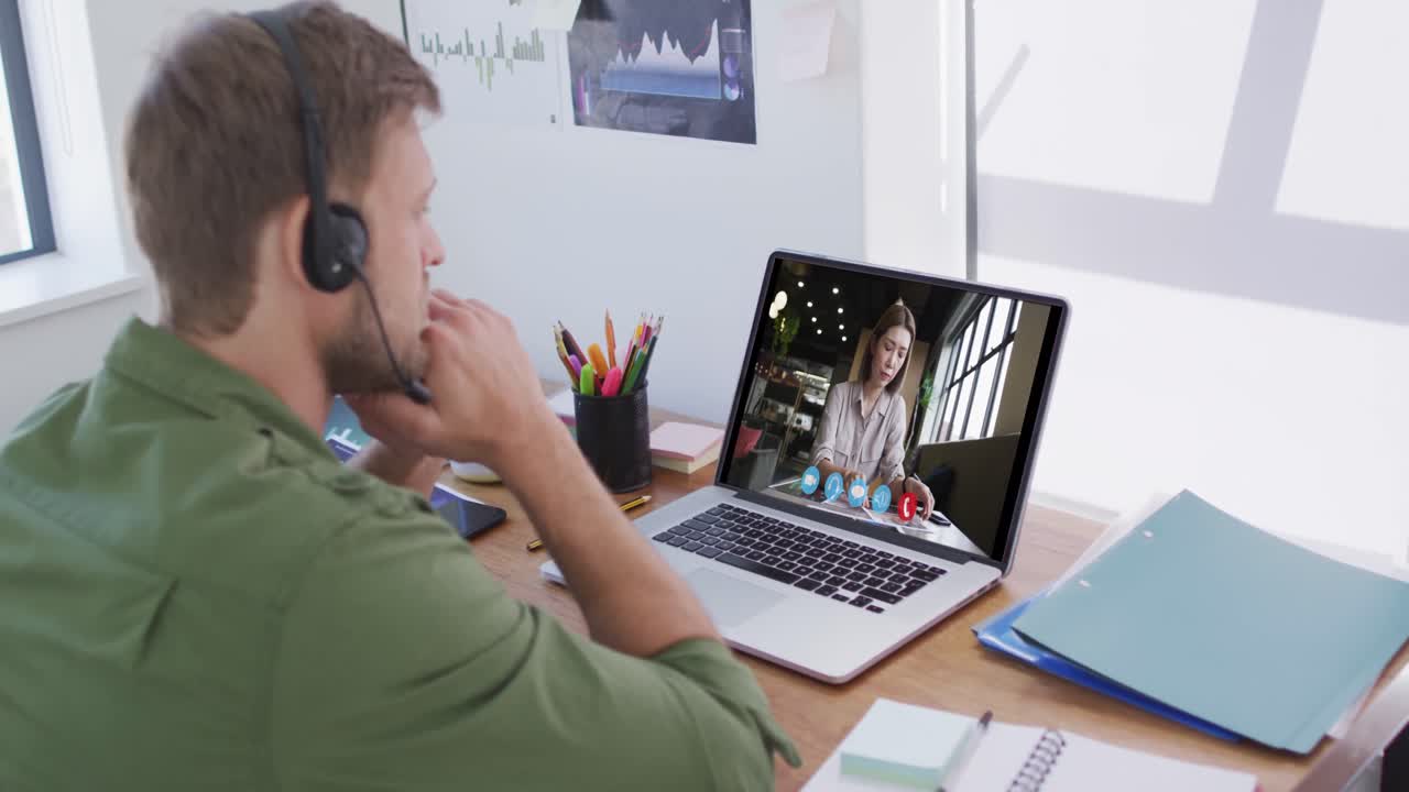 Kaukasisk mand bruger bærbar computer og telefonheadset på videoopkald med en kvindelig kollega.