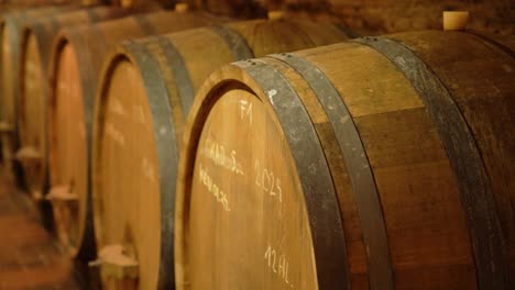 close-up of barrel tops showing handwritten chalk markings in wine cellar aging room