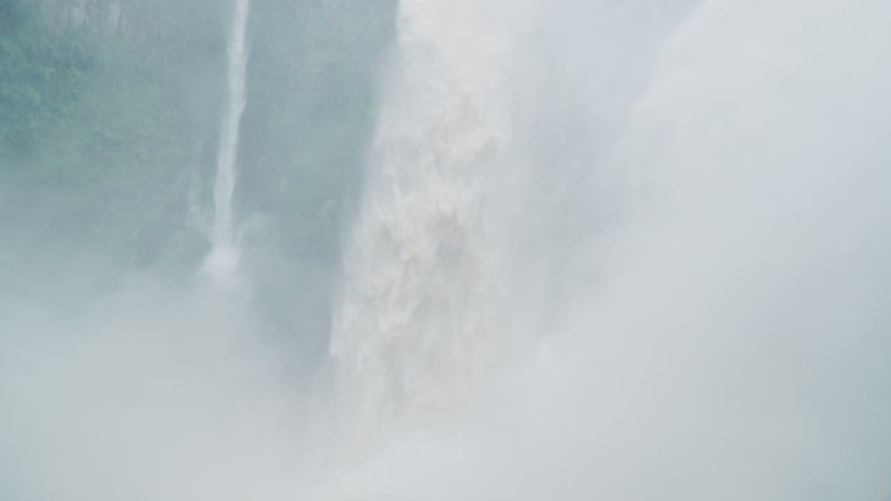 Man takes in Bajos del Toro waterfall and spray blowing off, slow motion