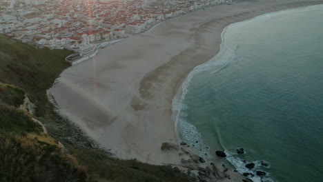 sunbeam over townscape on the sandy seashore of praia do norte , nazare portugal
