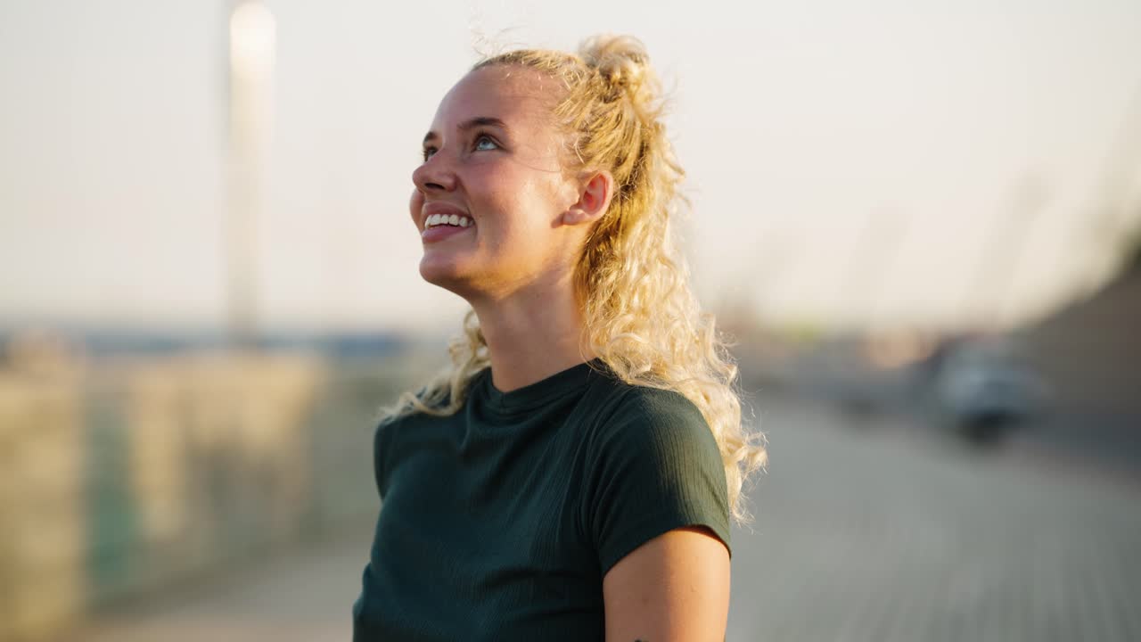 Žena s blond kudrnatými vlasy na mostě