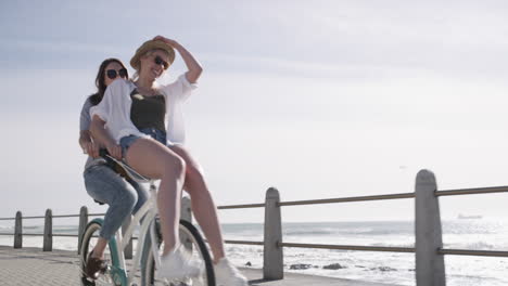 two young women riding a bicycle on the promenade