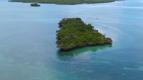 Circling-drone-shot-aroud-beautiful-tree-island-surrounded-by-turquoise-water