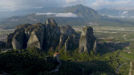 Cinematic aerial view of Meteora monastery in Greece perched on towering cliffs, dramatic rock formations and lush green valley create a breathtaking historic scene