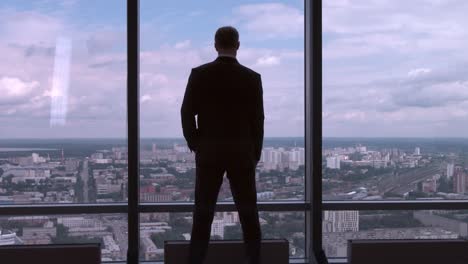 businessman looking out at the city from a skyscraper window