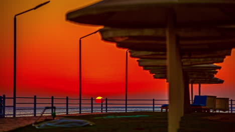 sun disappearing at horizon and beautiful orange sky over sea at sunset, day to night time lapse