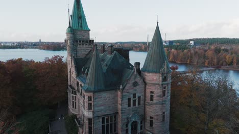 tracking shot towards teleborg castle in växjo, sweden, fall, orange and yellow leafs, drone closing in