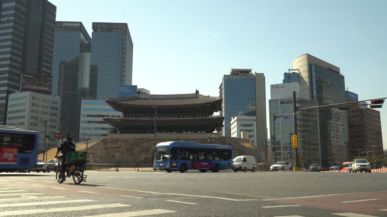 Busses fast passing Road intersection in front of Sungnyemun gate on downtown Seoul city background, South Korea.