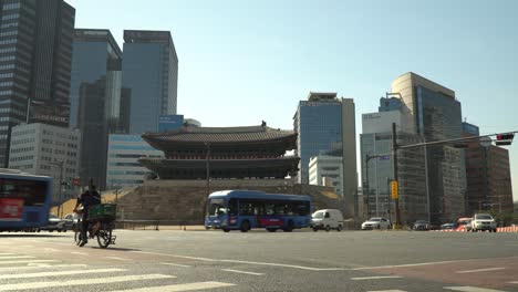 busses fast passing road intersection in front of sungnyemun gate on downtown seoul city background, south korea.