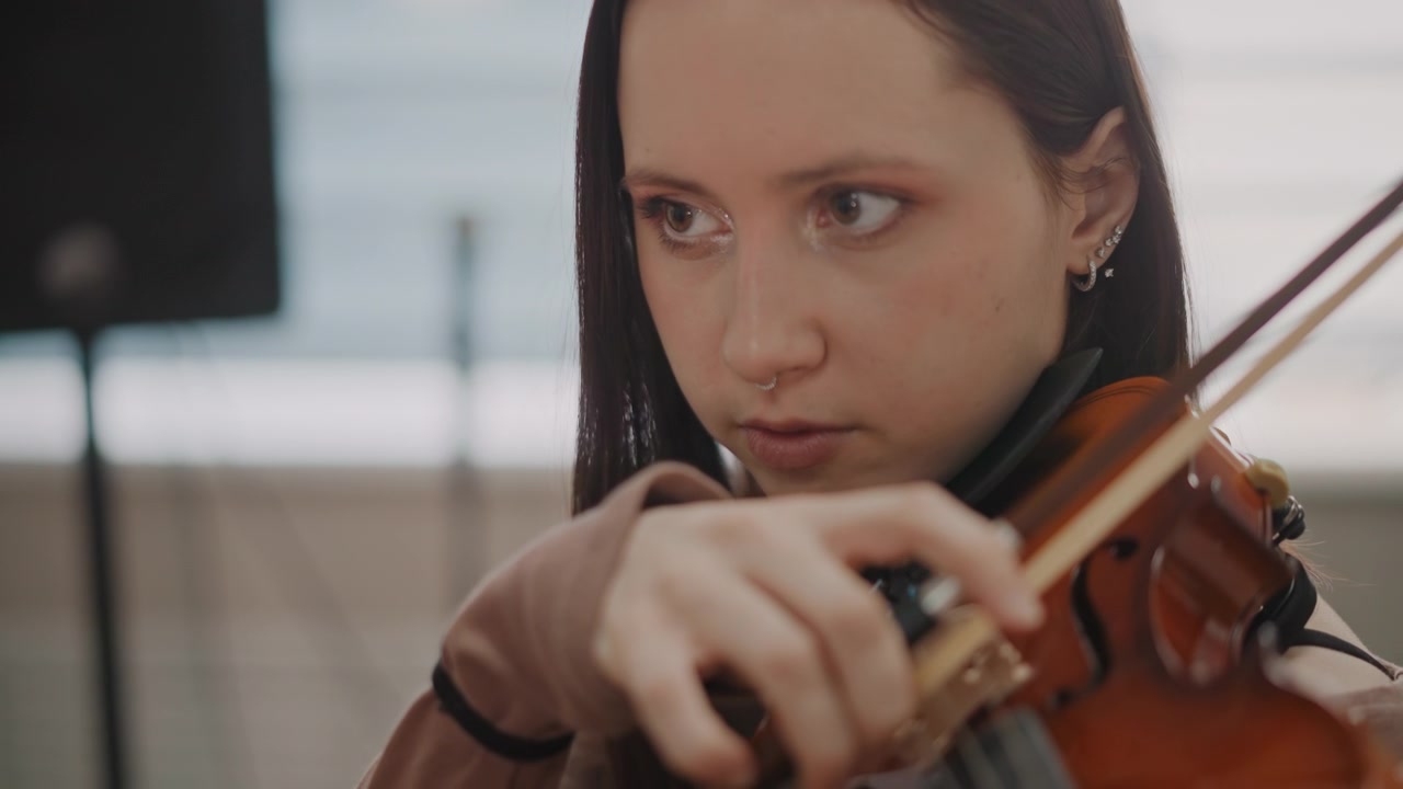 Estudante de violino concentrado intensamente em ambiente de gravação. Aluno dedicado mantendo a concentração durante a gravação com controle preciso do arco e ouvindo atentamente