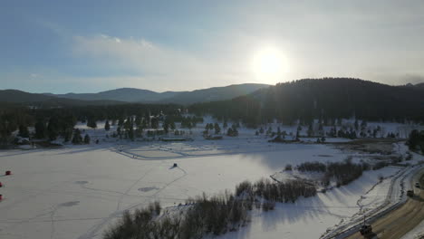 Sunset-Ice-skating-skate-hockey-rink-lake-pond-hockey-winter-Etown-Evergreen-Lake-house-fishing-tents-Denver-golf-course-Colorado-aerial-cinematic-drone-golden-hour-winter-snow-traffic-upward-motion