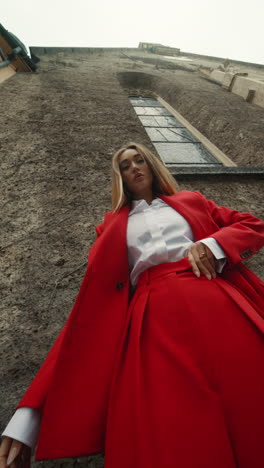 woman in red suit against a stone building