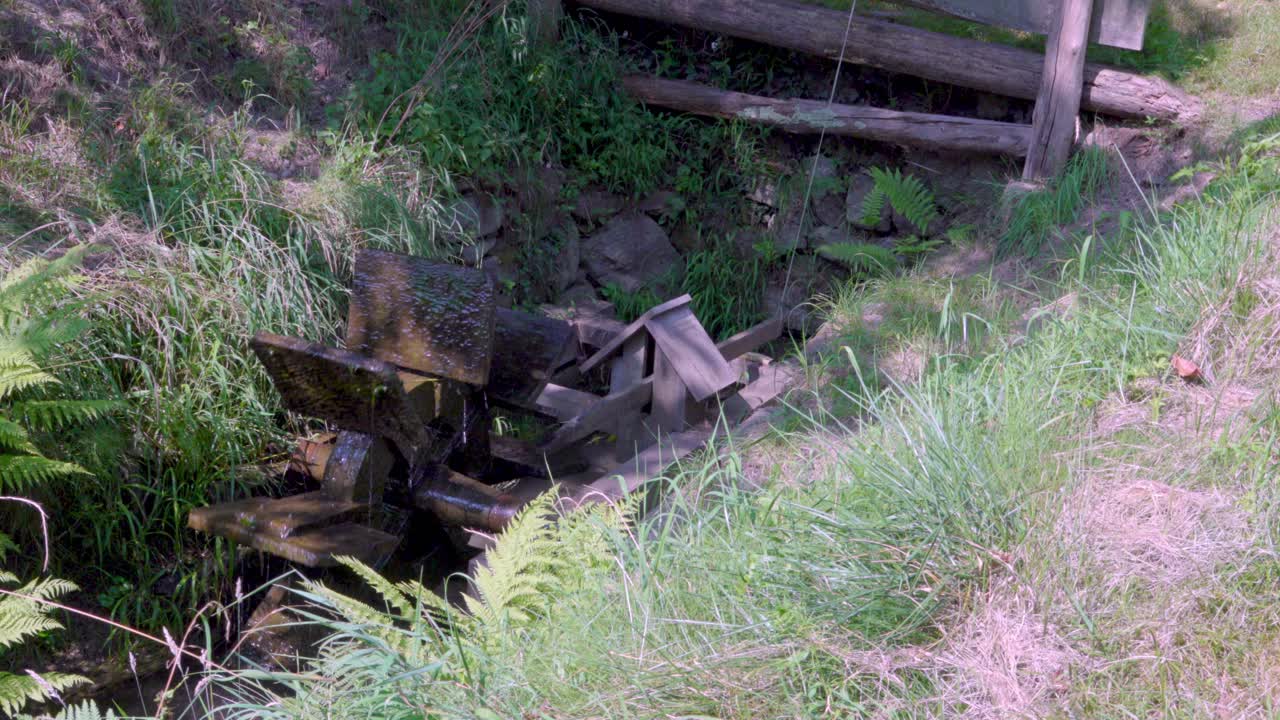 A small wooden water wheel that sets in motion a mechanism that controls the flow in an irrigation canal.