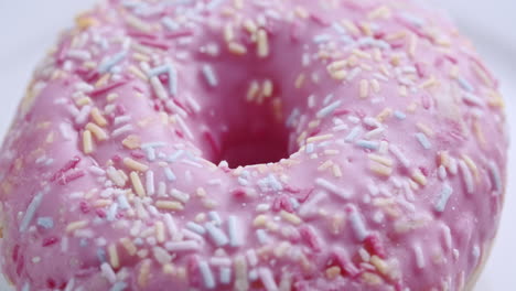 Close-up-shot-of-a-pink-donut-spinning-on-a-white-surface