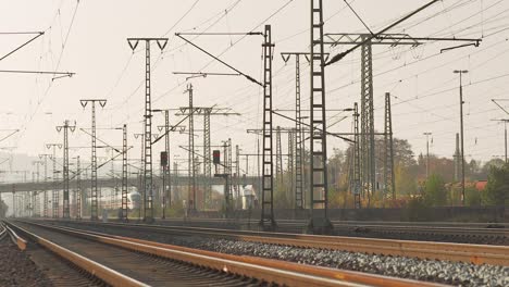 Sunset-glow-on-railway-tracks-with-complex-overhead-wiring-and-signals,-no-trains-visible,-empty-rails