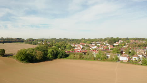 Rising-aerial-shot-over-a-field-with-London-underground-train-passing-in-the-background