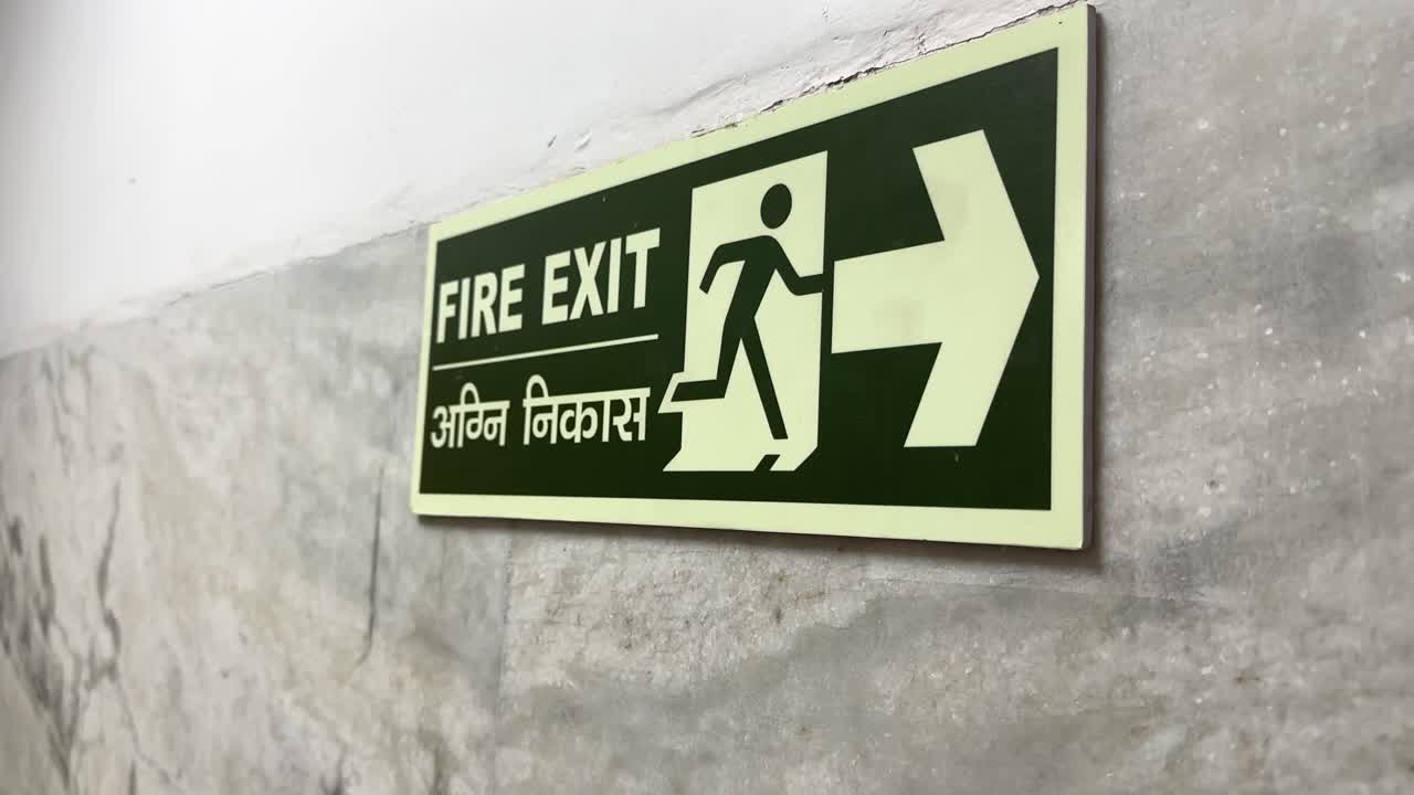 Close-Up Of Fire Exit Sign place on the wall to guide people in case of emergency written in english and hindi