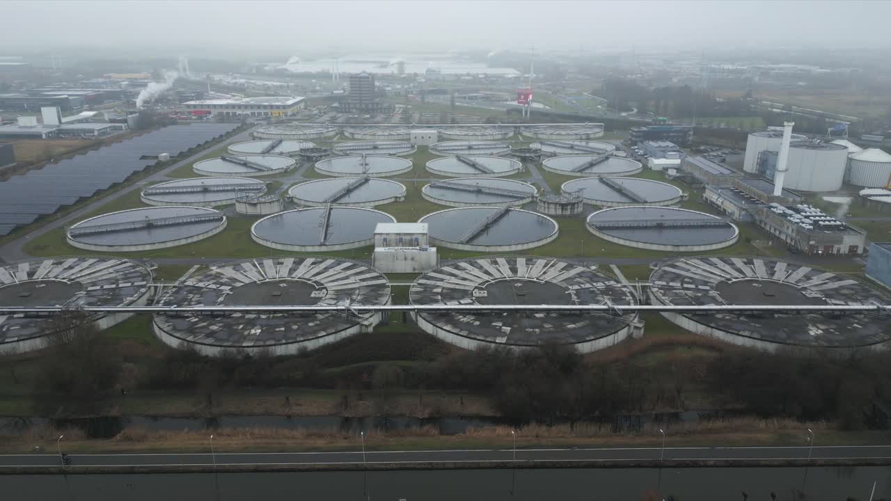 Wide drone aerial of Harnaschpolder wastewater treatment plant surrounded by industrial landscape, canals and Dutch water infrastructure