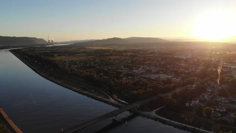 Aerial footage of the Rhine River in an industrial area with a bridge at dawn, showcasing the serene morning light reflecting on the water and structures.
